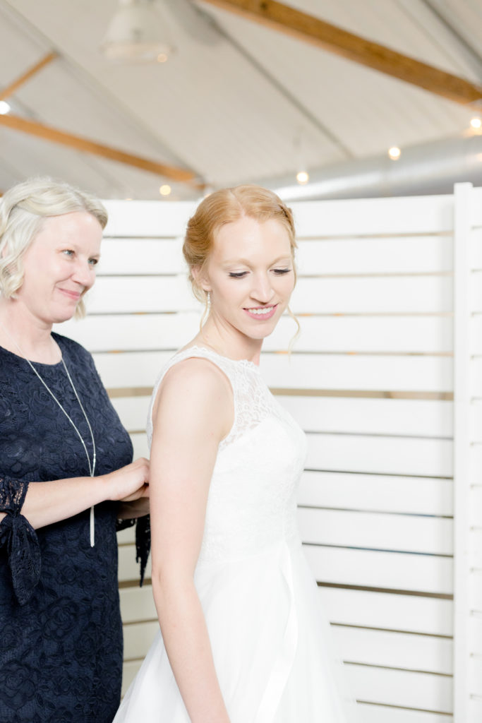 Bride gets into dress with the help of her mother at the Outpost Center in Chaska 