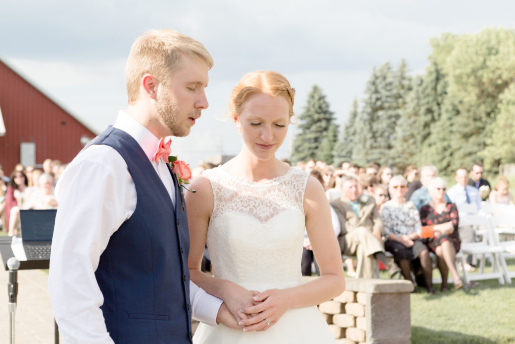 Bride and Groom pray together during their ceremony at the Outpost Center in Chaska