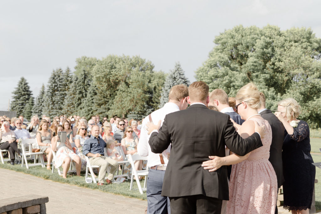 Bride and Groom's family pray over them during their ceremony at the Outpost Center in Chaska
