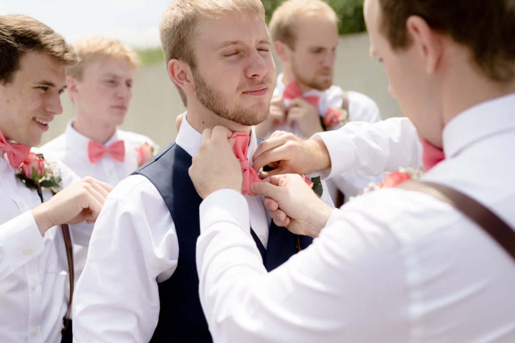 Groom getting ready at the Outpost Center in Chaska fixing his bowtie