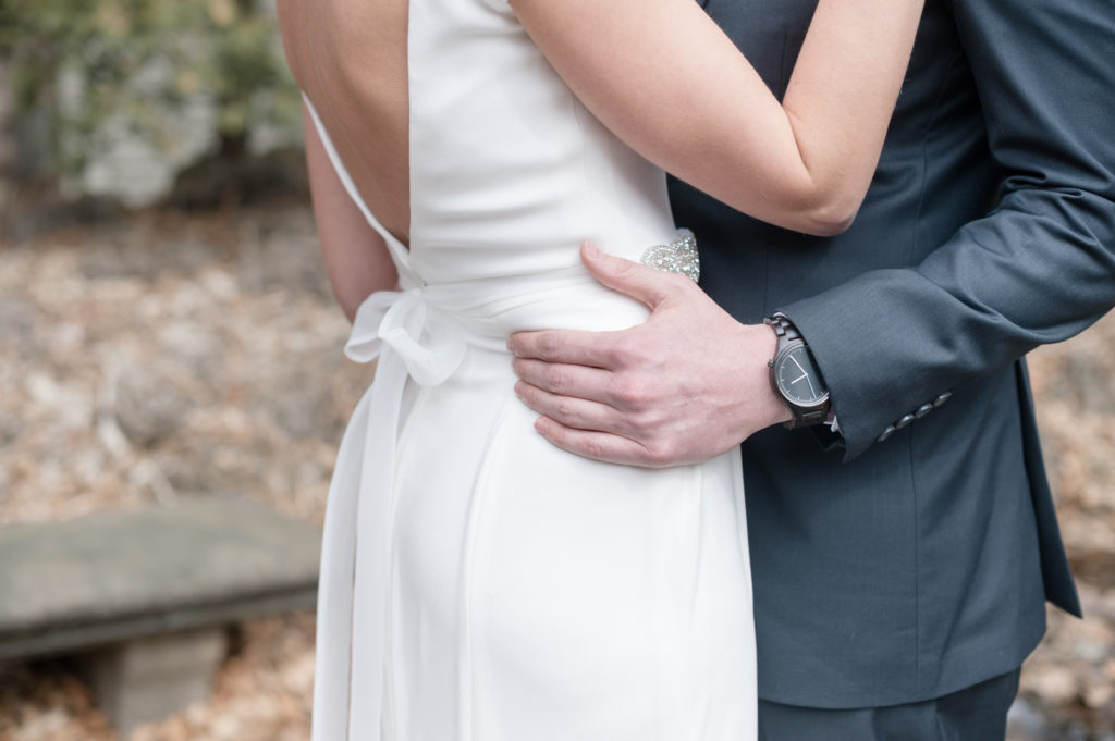 detail shot of the bride and groom holding each other